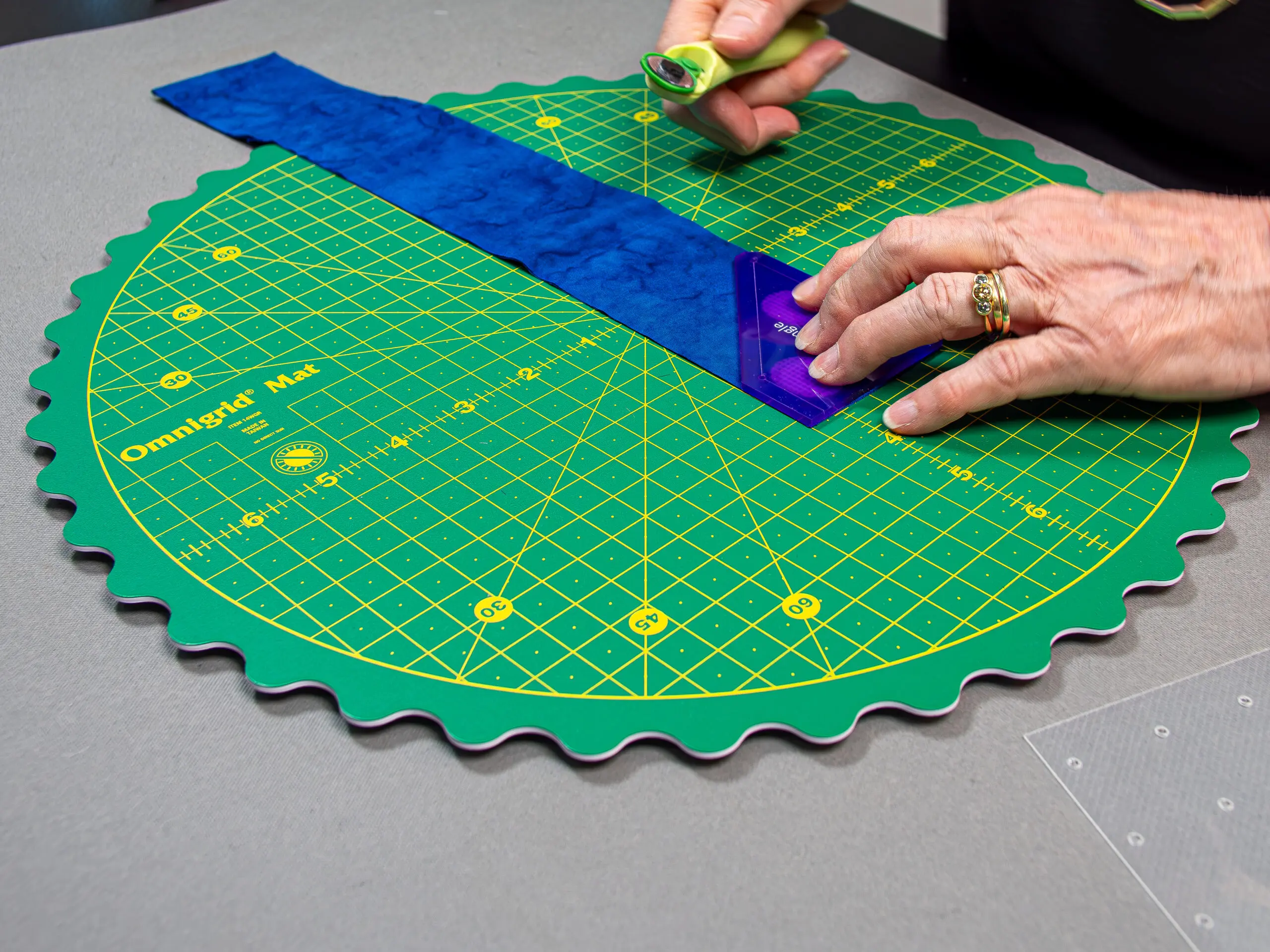 A clear quilting ruler with precise markings sitting on top of a green cutting mat.